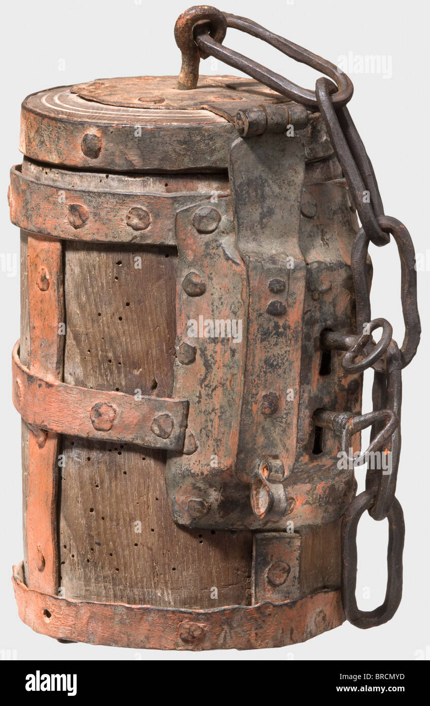 A heavy German money box, circa 1500 Cylindrical, turned oakwood case with intersecting iron straps. Hinged lid with slot, fastening chain and hasp. Riveted double lock on the side, with two keys. Red lead coat of later date, height 22 cm. The double lock with two keys suggests that this box was used as a guild box or for administrative purposes, as it could only be opened in the presence of two persons with corresponding keys. A very similar box with a double lock is depicted in Michael Trömner, Behältnisse für Kostbares 1500 - 1700, Abensberg 2006, pp. 30 f. , Stock Photo