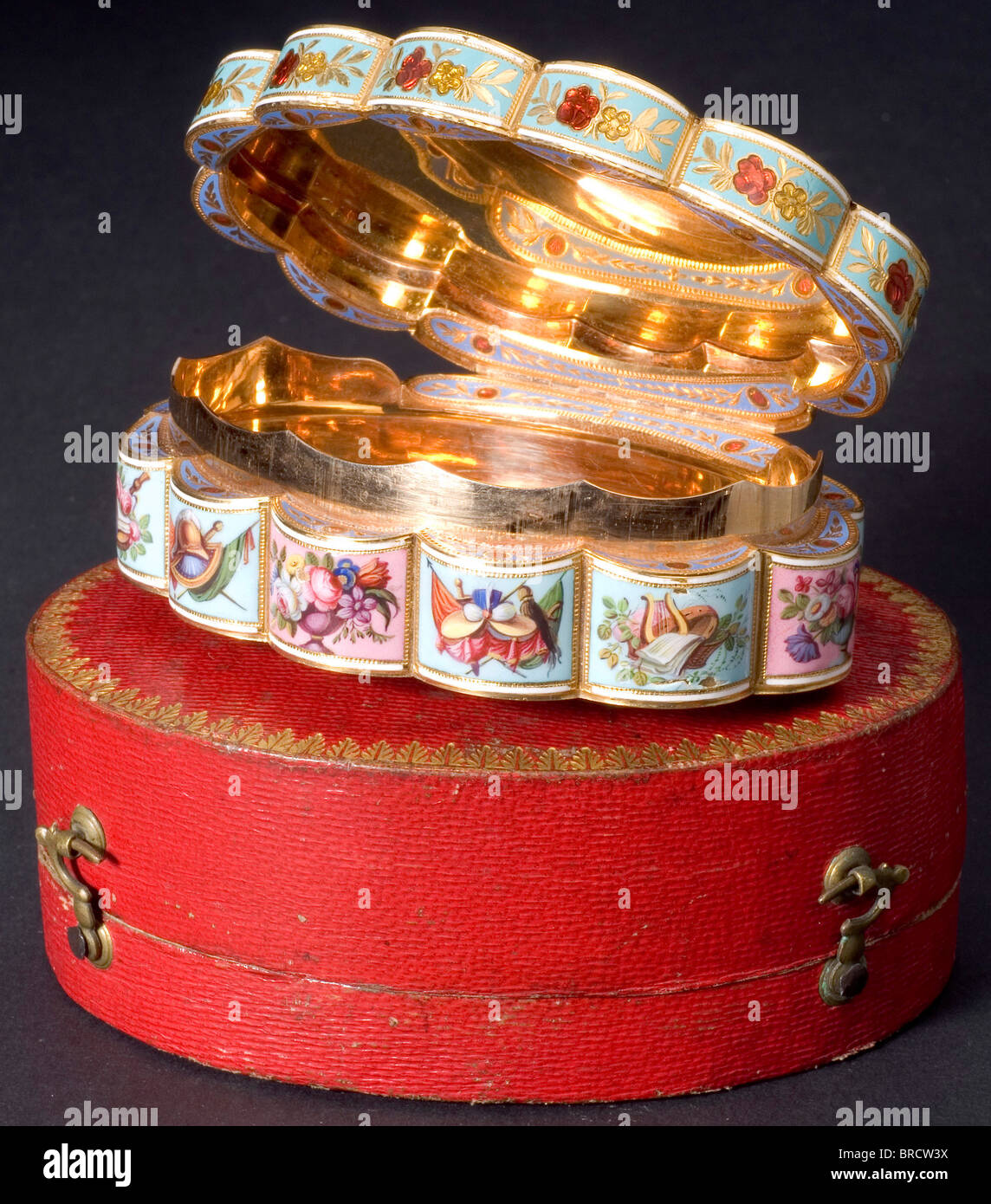 A fine enamelled gold box in a leather case, London, 1795/96 22-carat rose gold, enamelled, and hand painted. The entire surface of the twelve-section, oval box is enamelled. The top and bottom bear translucent red medallions on a guilloché background, displaying a hand-painted bouquet or a basket of flowers, set in turquoise flowery friezes with roses or flowers in yellow, red, and blue enamel. The rim of the lid is decorated en suite with flowers, and the lower edge bears twelve hand-painted cartouches on turquoise or rose-coloured enamel, displaying iridesce, Stock Photo