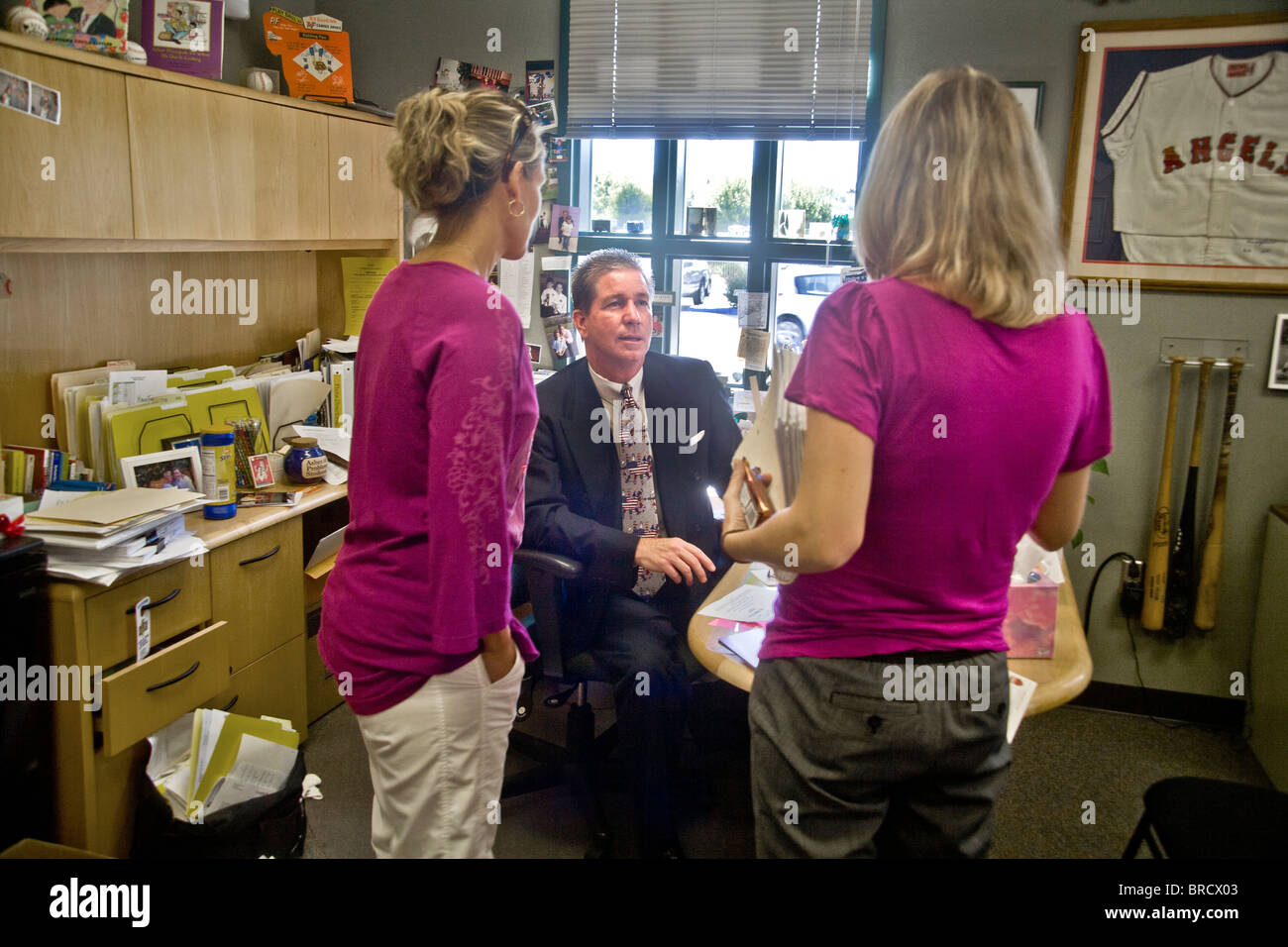 A Southern California school principal meets with two women teachers in his office. Stock Photo