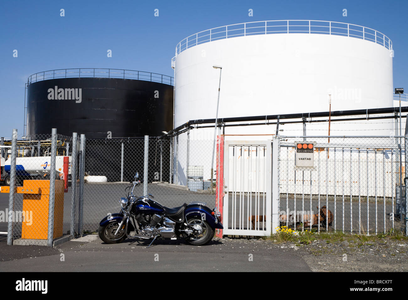 Motorcycle parked by oil/petrol tanks at Grandi, the fishpacking district. Reykjavik Iceland. Stock Photo