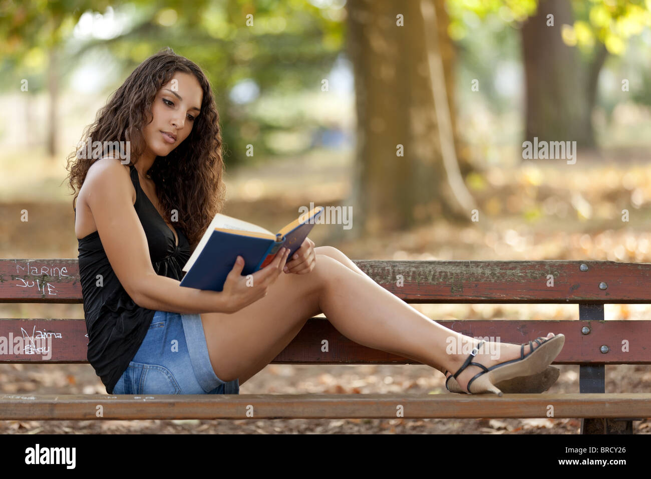 beautiful woman sitting on bench park reading book Stock Photo - Alamy