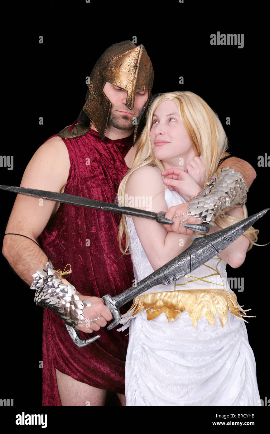one greek soldier holding a blonde goddess woman hostage over black Stock Photo