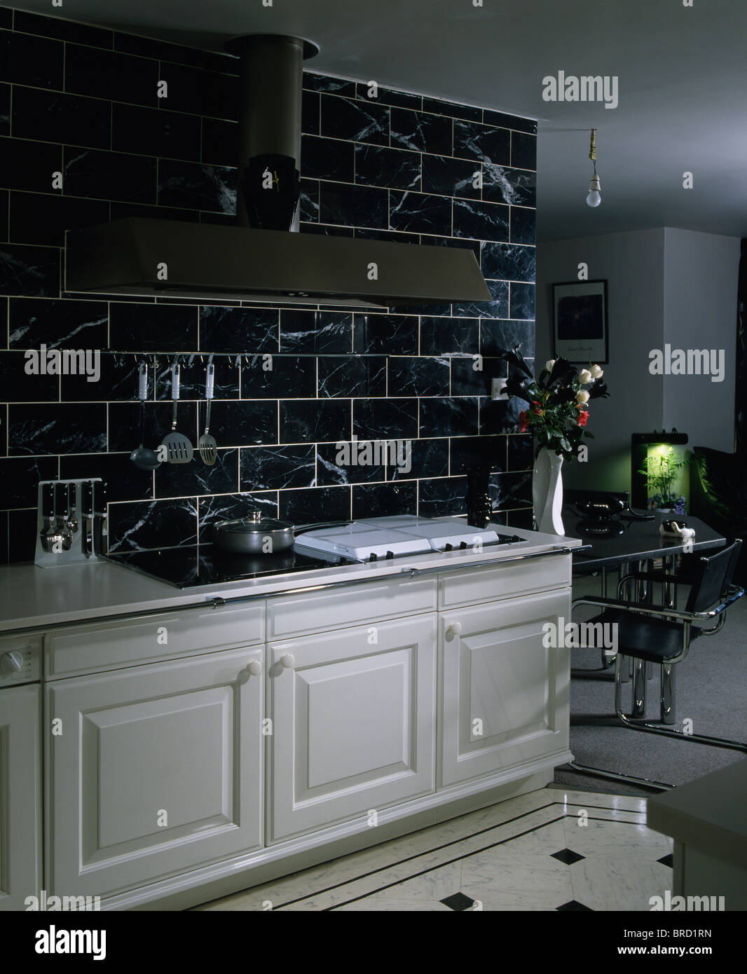 Black wall tiles above white fitted units in modern white kitchen Stock