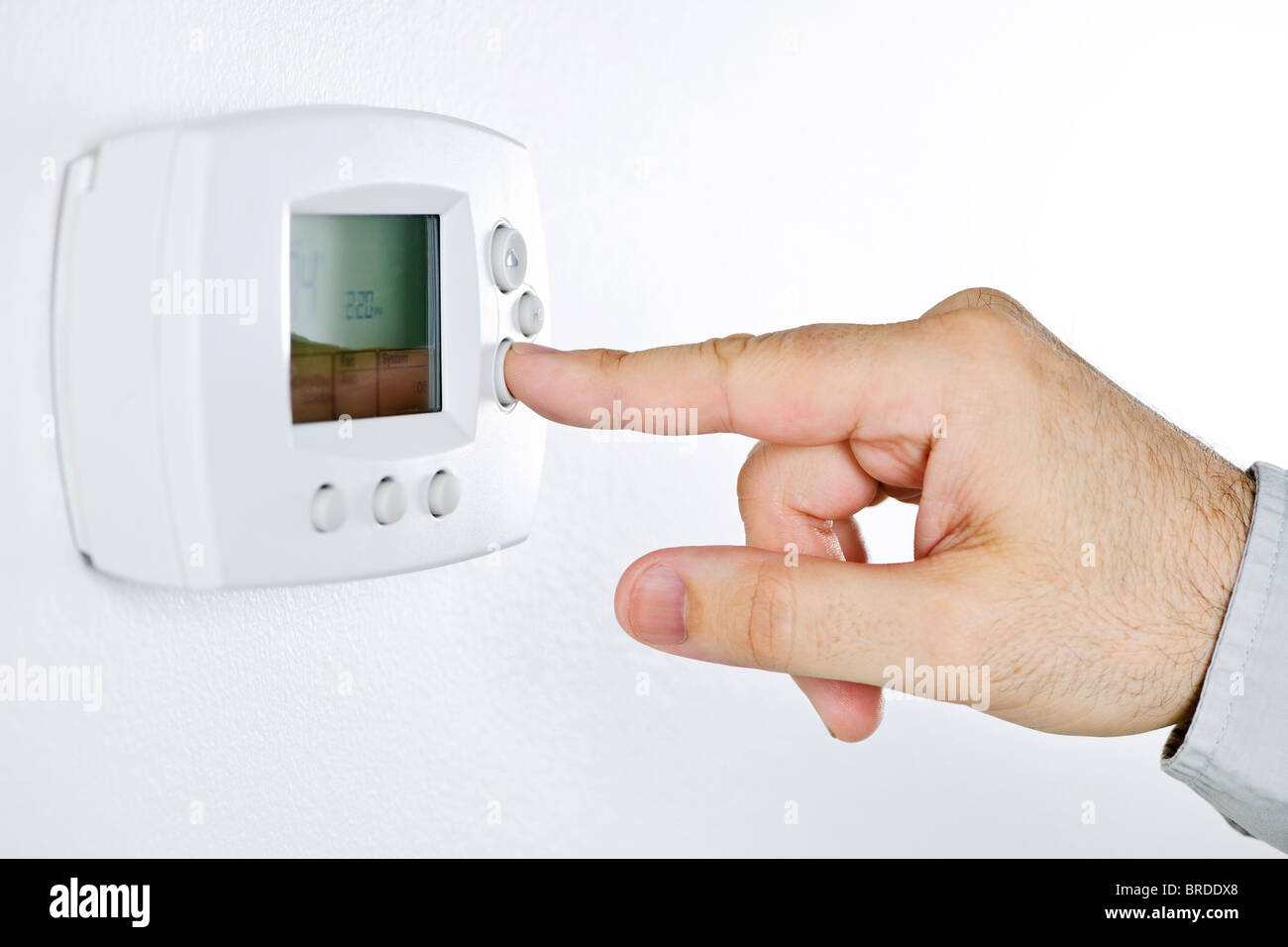 Closeup of hand pressing button on digital thermostat Stock Photo