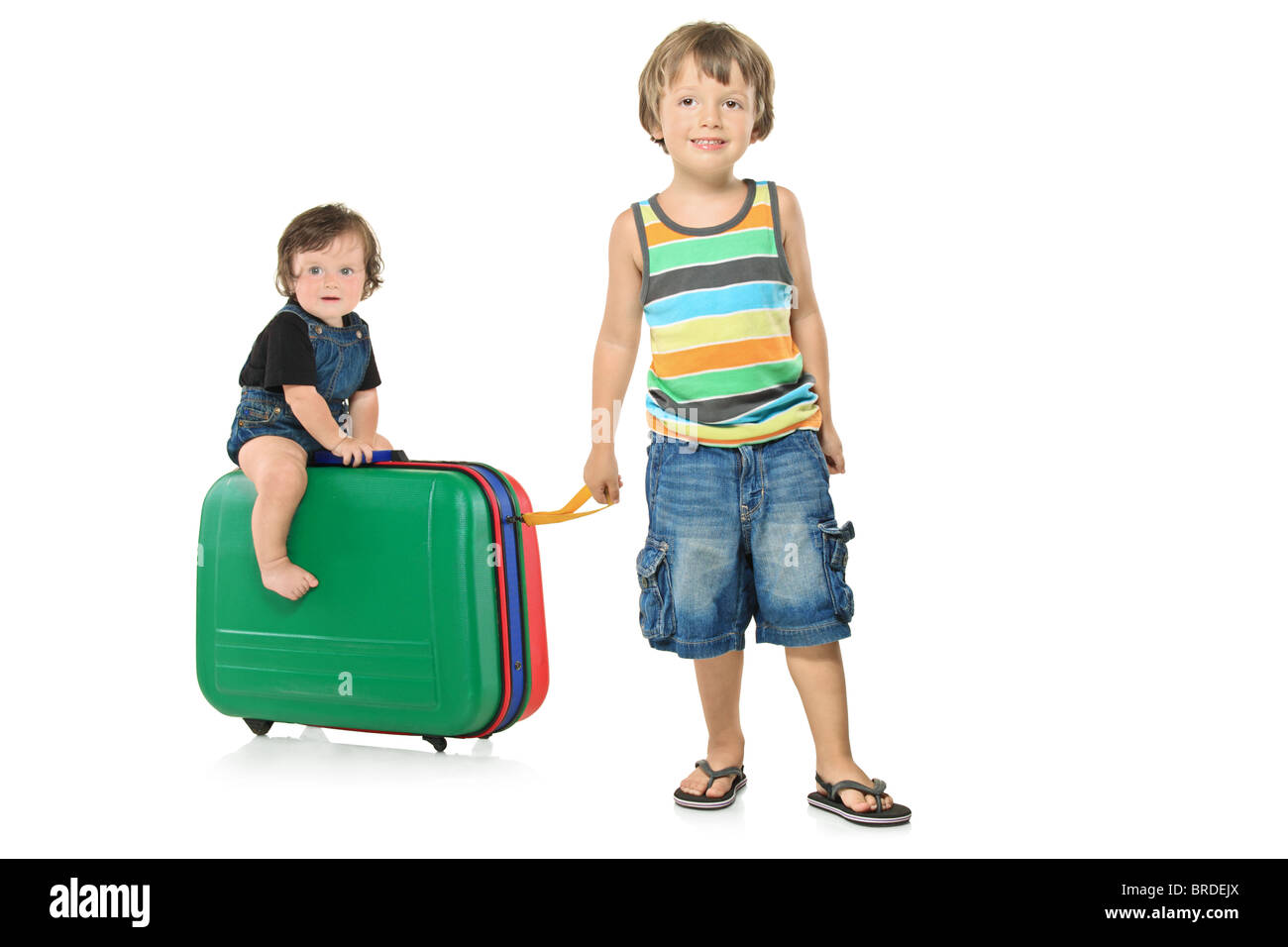 Full length portrait of a boy pulling a suitcase with a baby boy on it Stock Photo Alamy