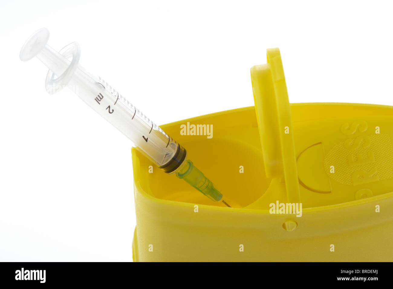 disposing of a hypodermic syringe and needle in a yellow plastic sharps box Stock Photo