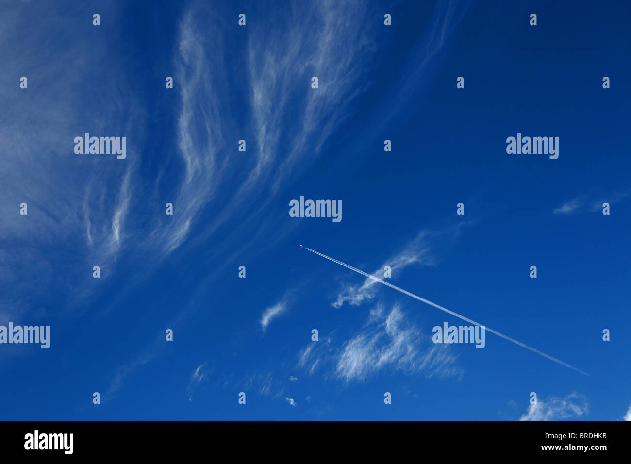 Cirrus spissatus clouds high above Somerset with an aircraft leaving a vapour vapor trail contrail Stock Photo