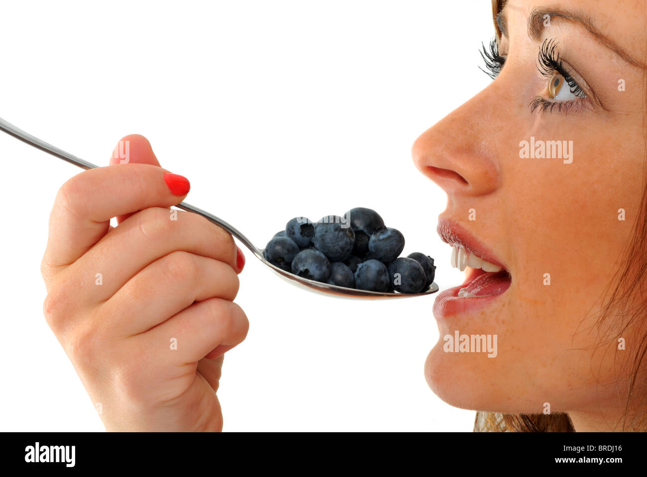 Blueberries, woman eating a spoonful of blueberries Stock Photo