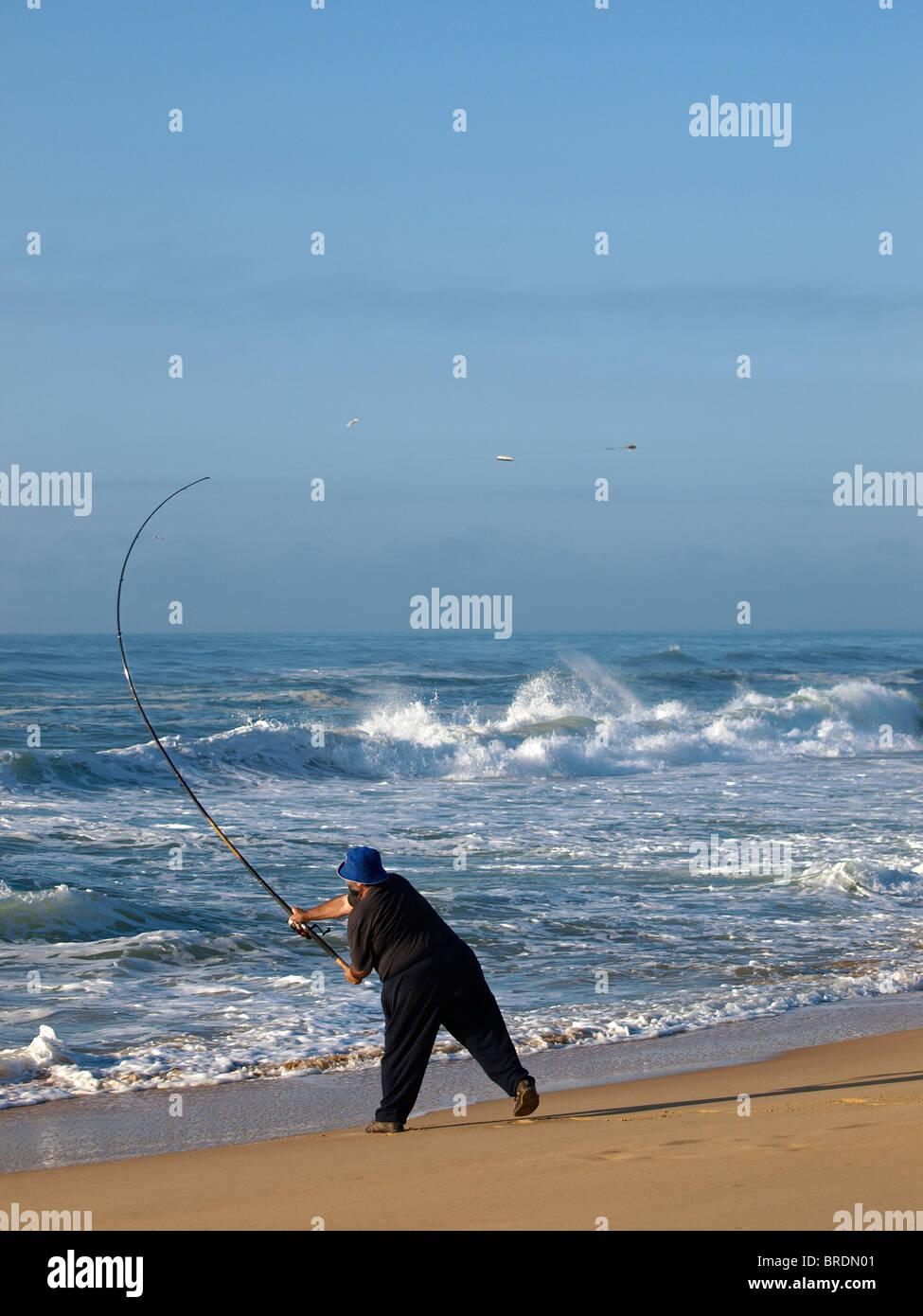 FISHERMAN CASTING INTO THE SEA FROM BEACH AT  NINETY MILE BEACH GIPPSLAND VICTORIA AUSTRALIA Stock Photo