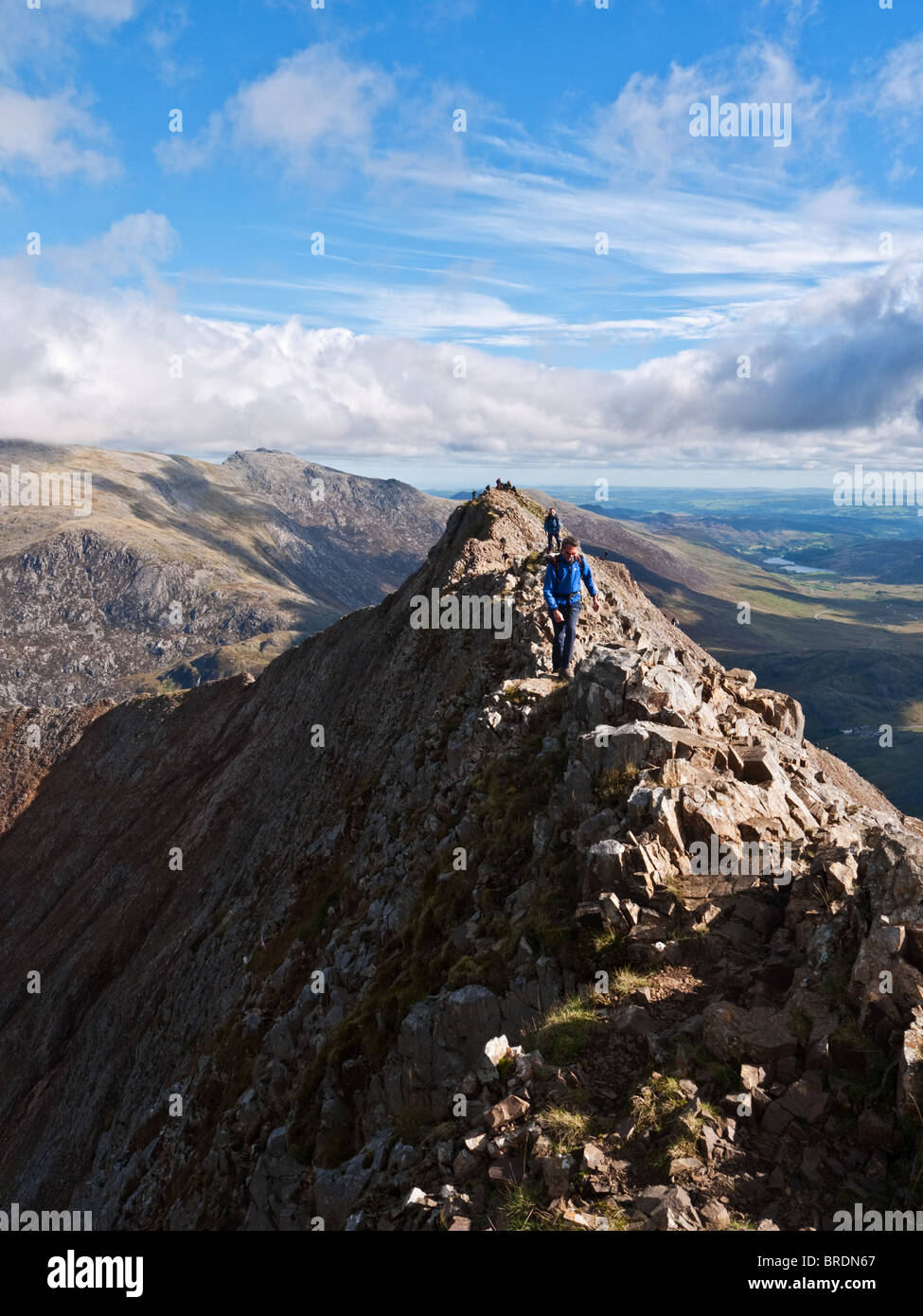 A walker crosses the arete of Crib Goch, a ridge traverse in Snowdonia forming the first section of the Snowdon Horseshoe walk Stock Photo