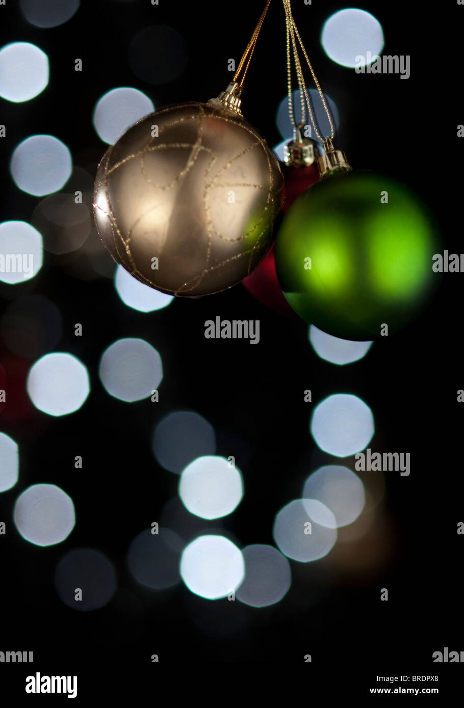 Three Christmas decoration balls. Blurry lights on background. Stock Photo