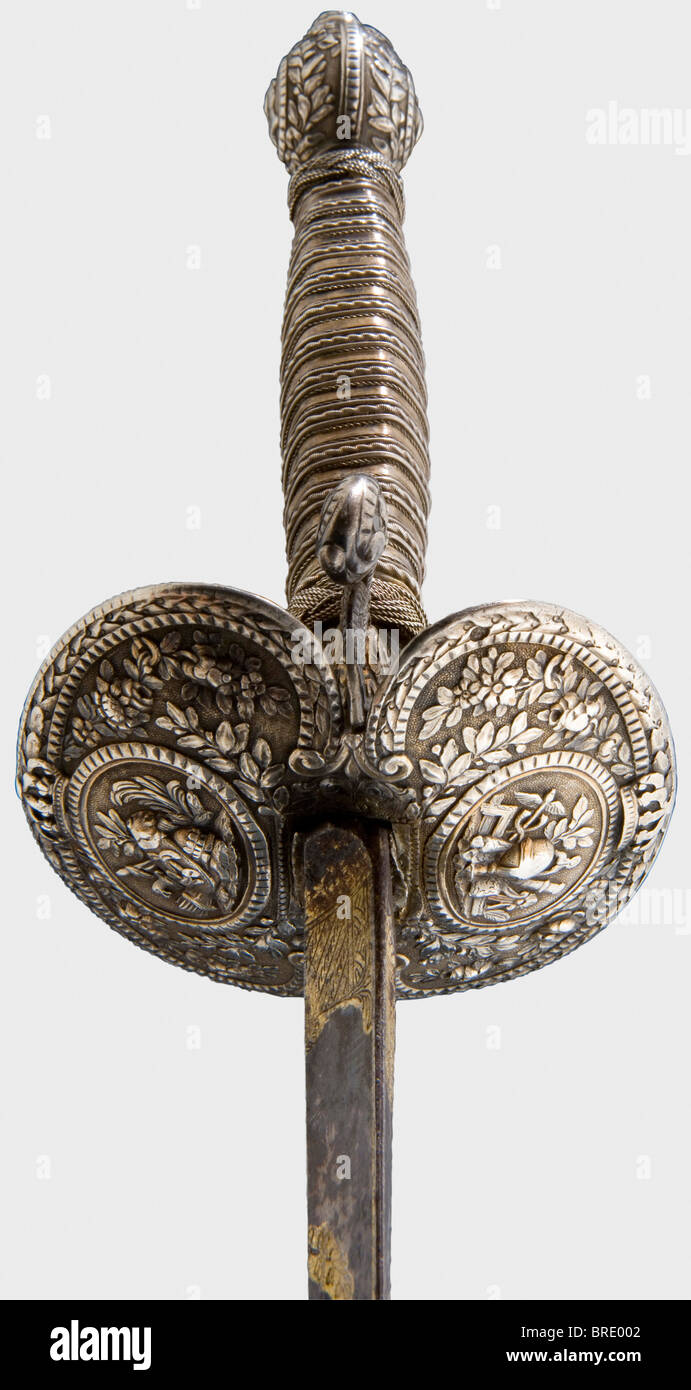 A French silver-hilted small-sword, Paris, 1775 Hollow triangular thrusting blade etched and gilt on a blued panel (mostly preserved ) on the reverse side. Silver hilt with remnants of gilding in floral relief with martial trophies within oval cartouches, each beneath a royal crown. Double shell-guard with the reverse cipher 'L' on the outside, and three fleur-de-lys within an oval coat-of-arms on the inside. The arms of the hilt is stamped with an 'M' beneath a crown, for Paris 1775. A of Louis XVI on one side of the pommel. Original silver wire boung grip wit, Stock Photo