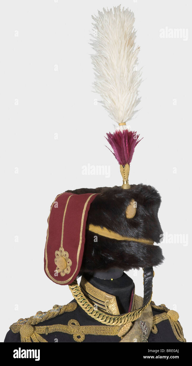A uniform for a Captain, of the 11th Hussars (Prince Albert's Own) Fur cap of black sable, crimson red kolpak, braided golden lanyards, two-colour plume of ostrich and vulture feathers, and gilded metal chinstrap. Dark blue, cloth atilla with gold lace and gold cording. Crimson red trousers with yellow leg stripes. Also the bandolier set with silver cleaning-pick fitting, the cartridge box with a lid of gilt brass adorned with silver overlay, and a red leather sword belt set-off with gold lace. It comes with the protective case for the fur cap and plume as well, Stock Photo
