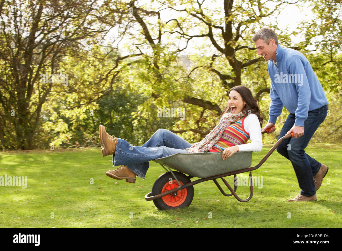 Couple With Man Giving Woman Ride In Wheelbarrow Stock Photo