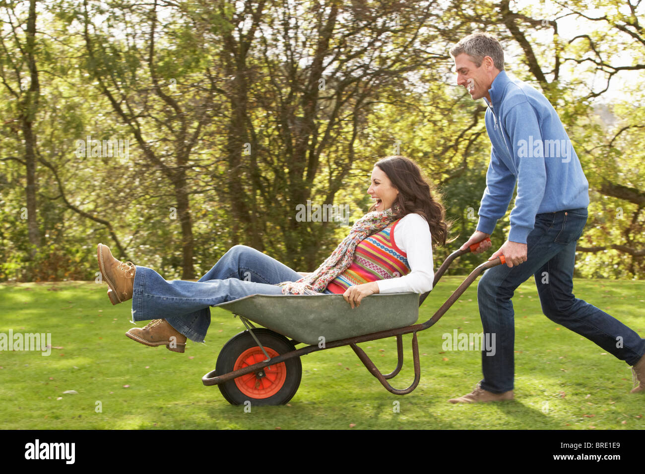 Couple With Man Giving Woman Ride In Wheelbarrow Stock Photo