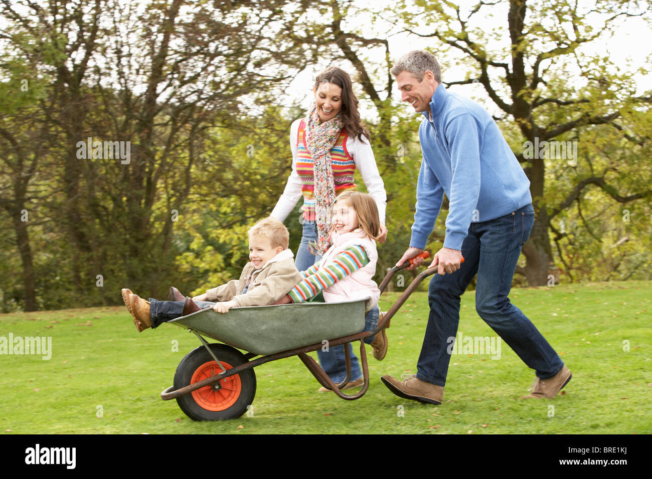 Parents Giving Children Ride In Wheelbarrow Stock Photo - Alamy