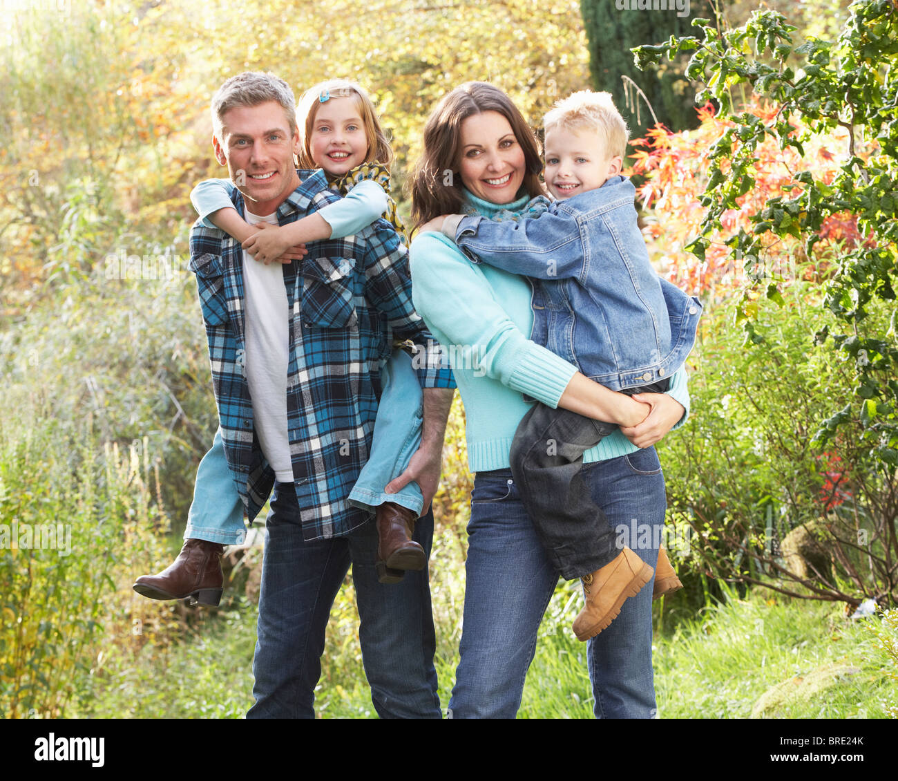 Family Group Outdoors In Autumn Landscape With Parents Giving Chiildren Piggyback Stock Photo