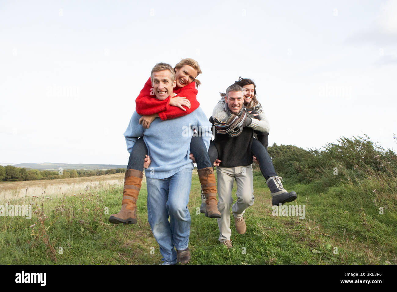 Two Couples Having Piggyback Ride In Autumn Landscape Stock Photo - Alamy