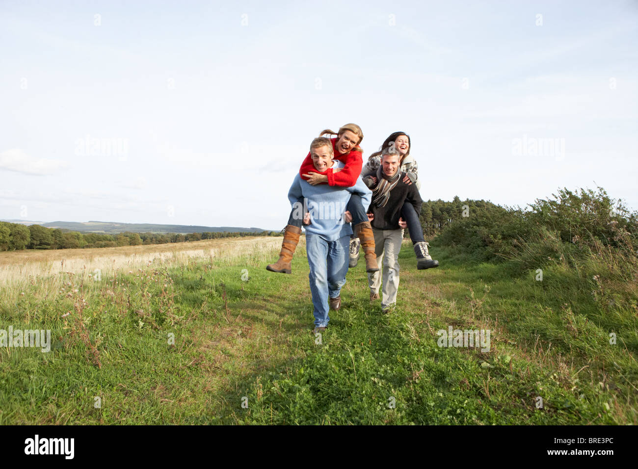 Two Couples Having Piggyback Ride In Autumn Landscape Stock Photo - Alamy