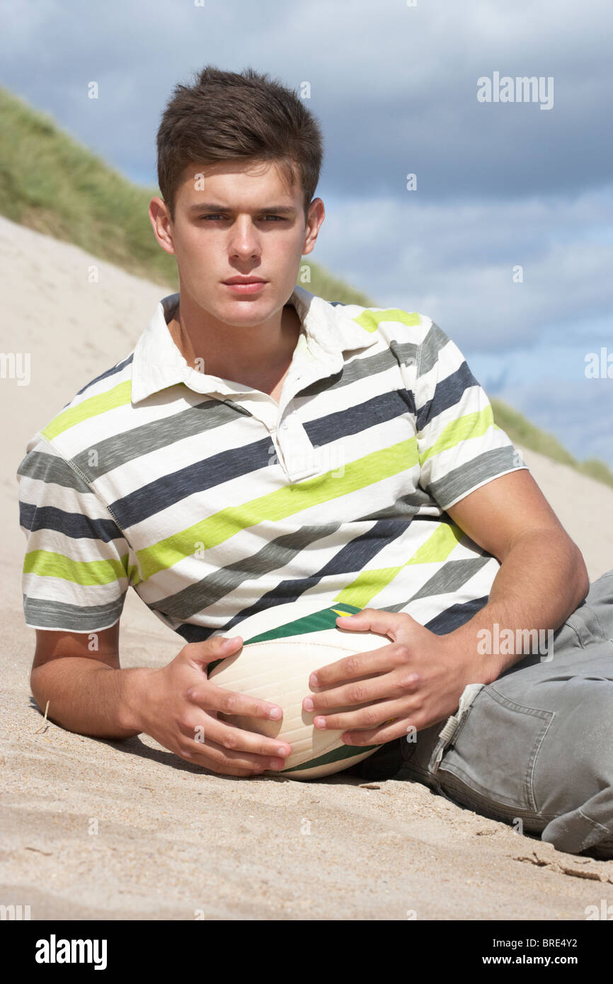 Teenage Boy Sitting On Beach Holding Rugby Ball Stock Photo Alamy