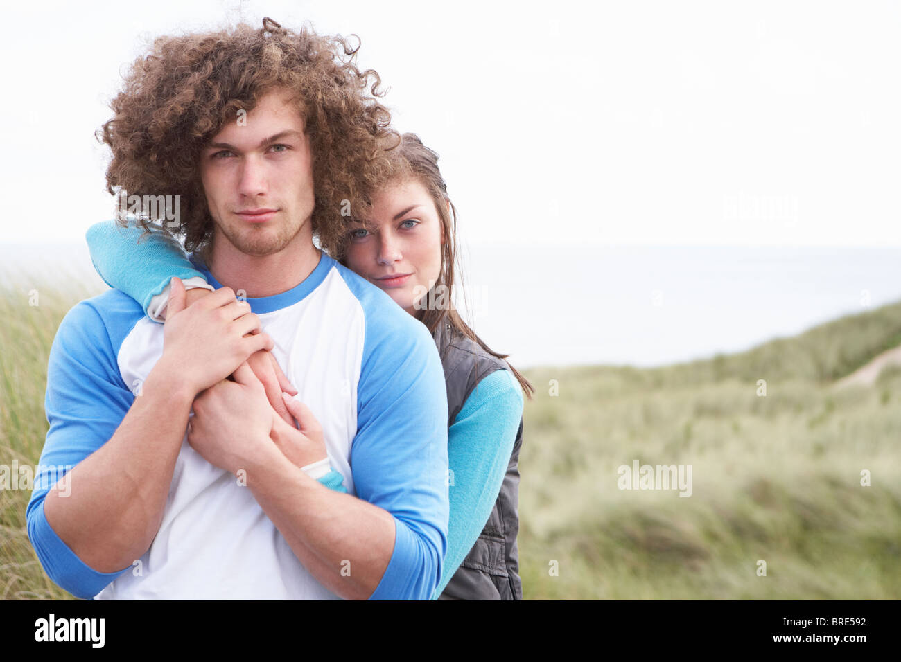 Young Couple Walking Through Sand Dunes Wearing Warm Clothing Stock Photo