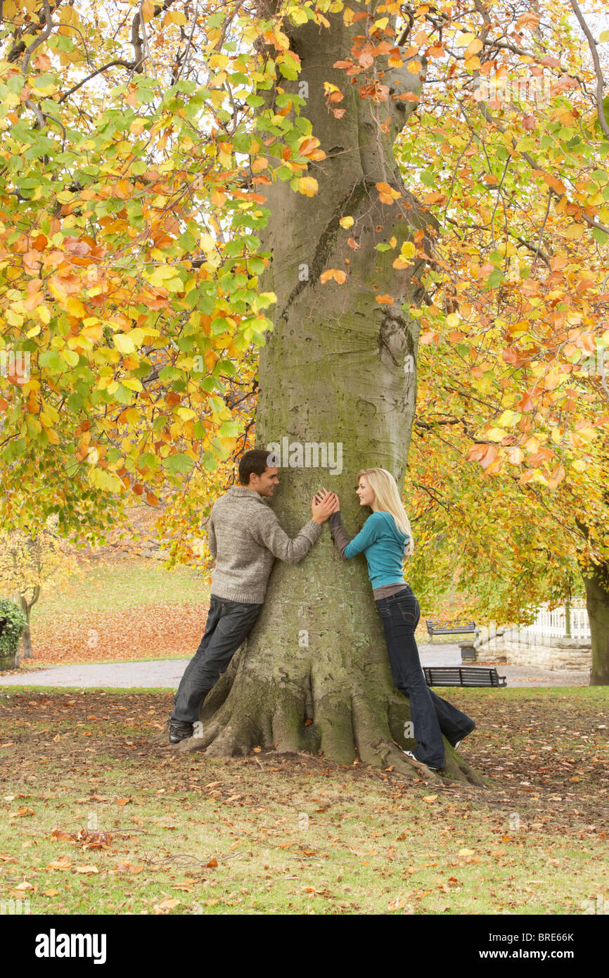 Romantic Teenage Couple By Tree In Autumn Park Stock Photo