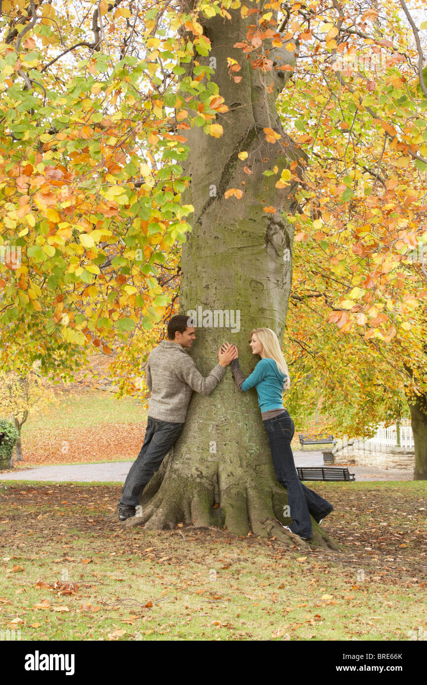 Romantic Teenage Couple By Tree In Autumn Park Stock Photo - Alamy