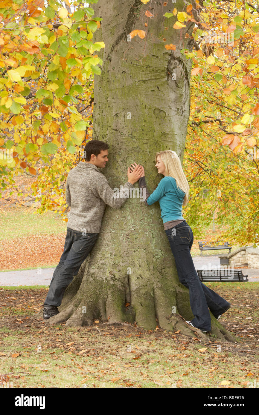Romantic Teenage Couple By Tree In Autumn Park Stock Photo - Alamy