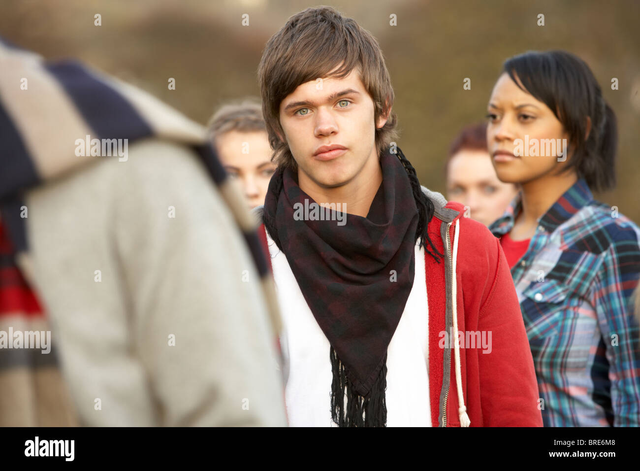 Teenage Boy Surrounded By Friends In Outdoor Autumn Landscape Stock Photo