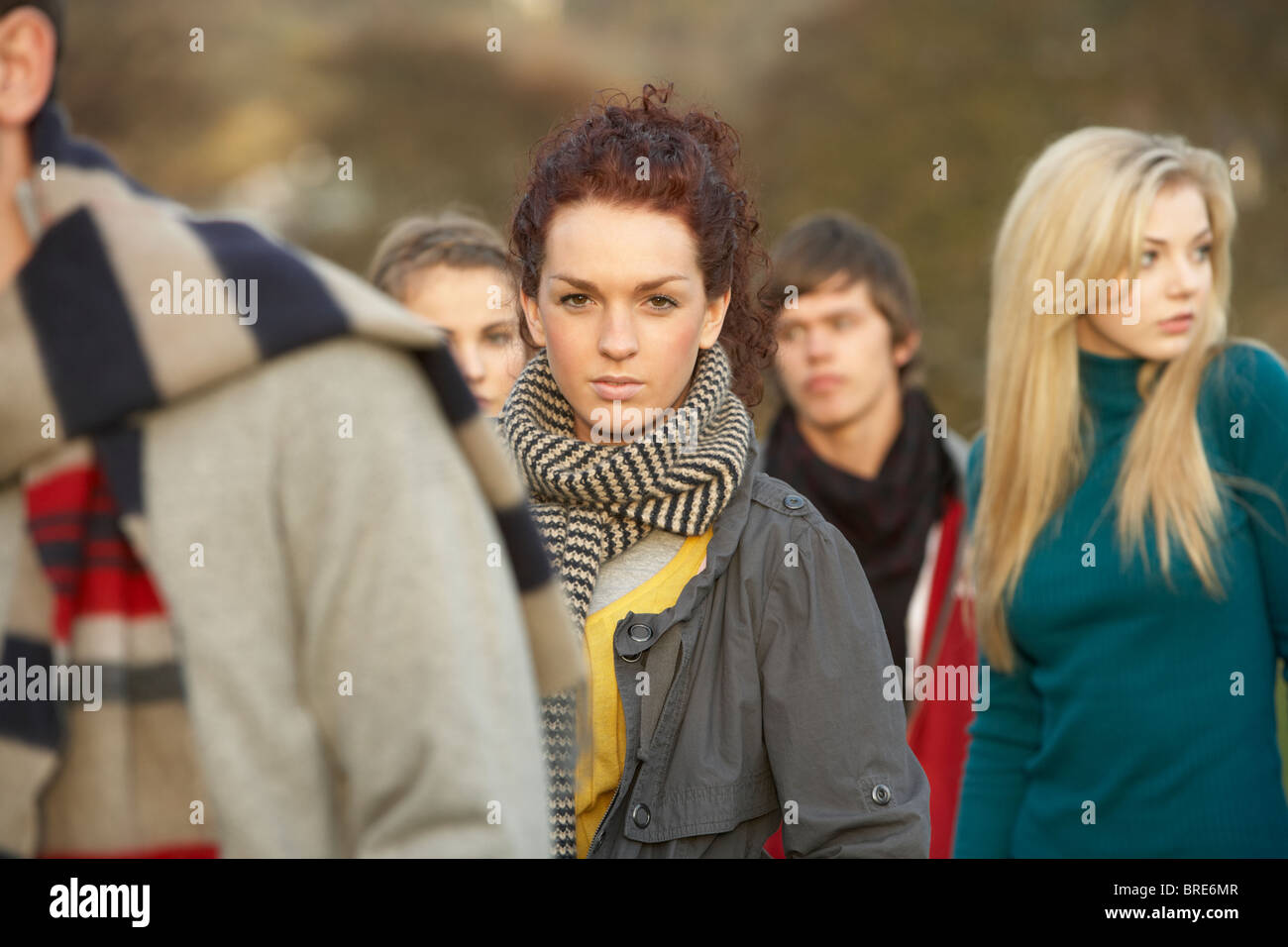 Teenage Girl Surrounded By Friends In Outdoor Autumn Landscape Stock Photo