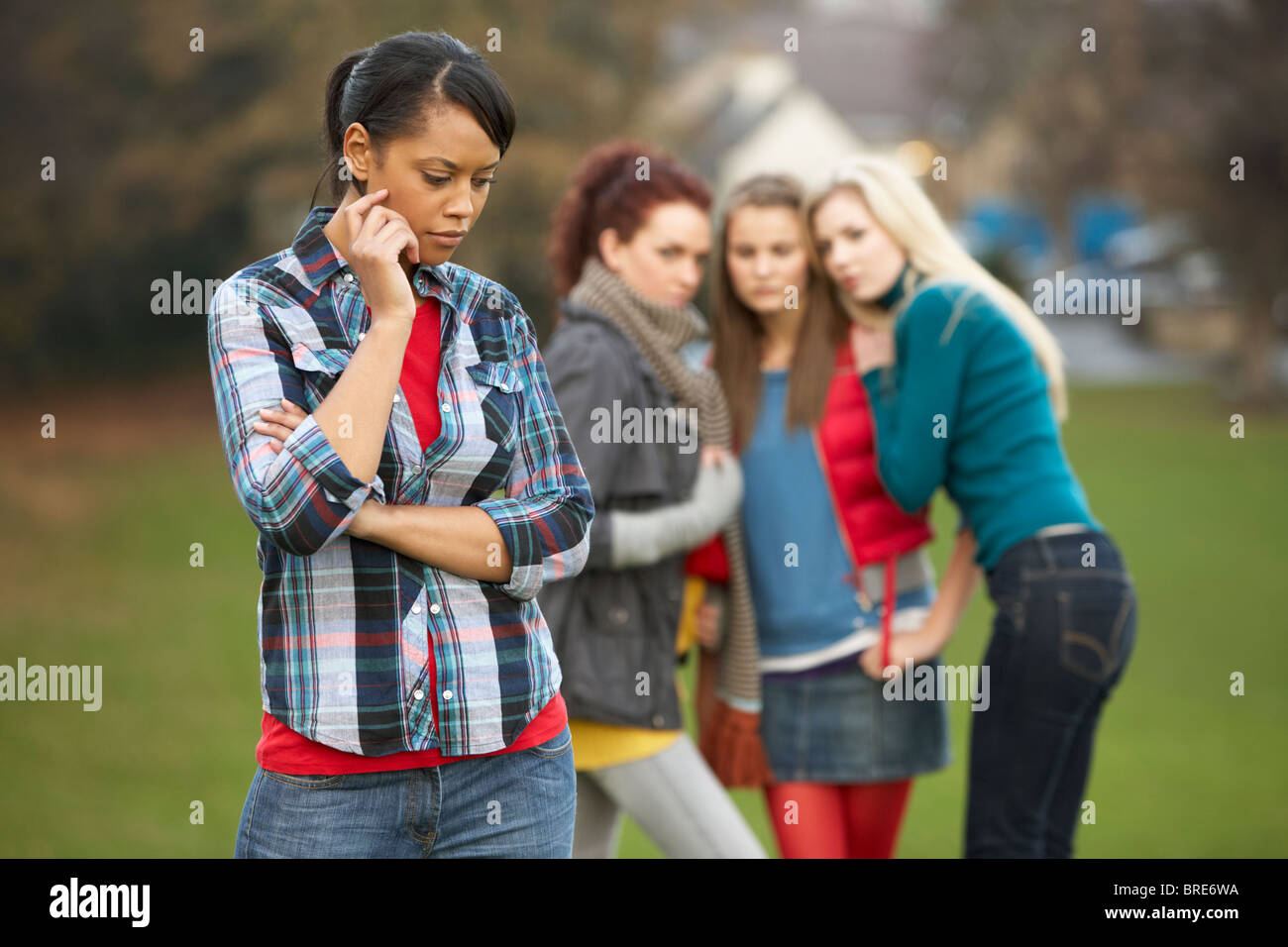 Upset Teenage Girl With Friends Gossiping In Background Stock Photo