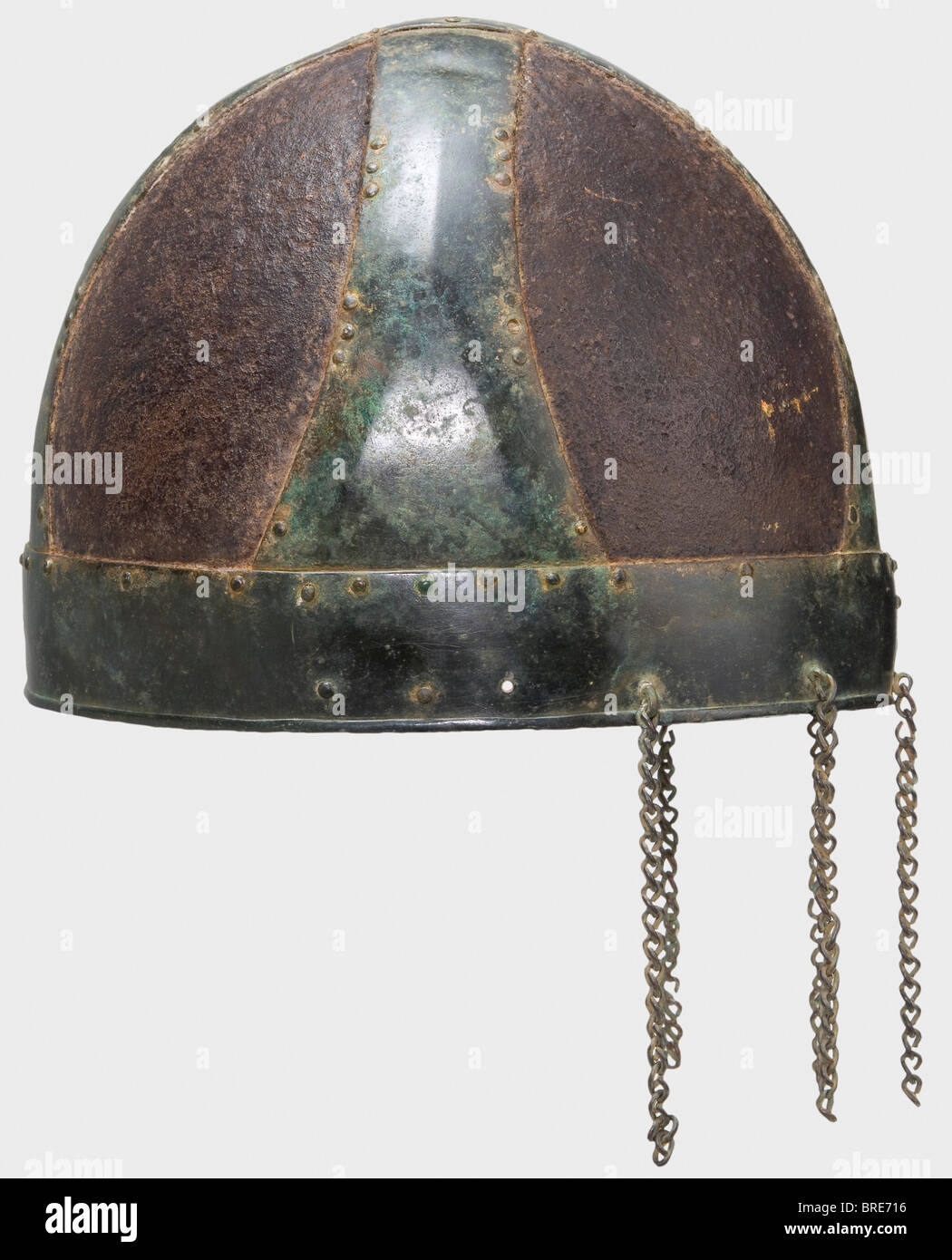 A 'Spangenhelm', Migration Period, 6th century Iron skull made in four pieces with overlapping bronze bands forming a cross. The slightly ridged helmet bands taper from wide bases, and are riveted to the skull pieces along the rims. A surrounding brow band with a turned under rim riveted to the lower edge. Five loops at the nape of the neck with hanging bronze chains about 10 cm long. The iron plates rusted through in places. Cleaned excavation find. Height 17.5 cm. historic, historical, ancient world, defensive arms, weapons, arms, weapon, arm, fighting device, Stock Photo