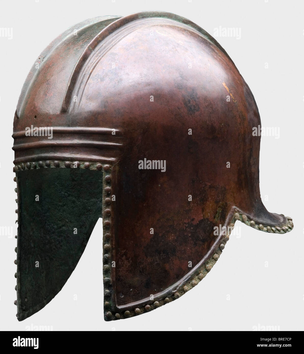 An Illyrian helmet, 6th century B.C. Bronze Domed skull with a broad crest base distinctly offset by high, strongly contoured ridges. Large face cutout, brow with reinforcing ribs, cheek pieces with holes. Lightly flaring neck-guard, the perimeter of the helmet decorated with lentil-headed rivets (all rivets present!) under a raised reinforcement border. Height 23 cm. Weight 1000 g. Red brown patina, metallic surface in places. Axel Guttmann Collection (no inventory number). Cf. similar helmets from the Axel Guttmann Collection in Hermann Historica's 49th aucti, Stock Photo