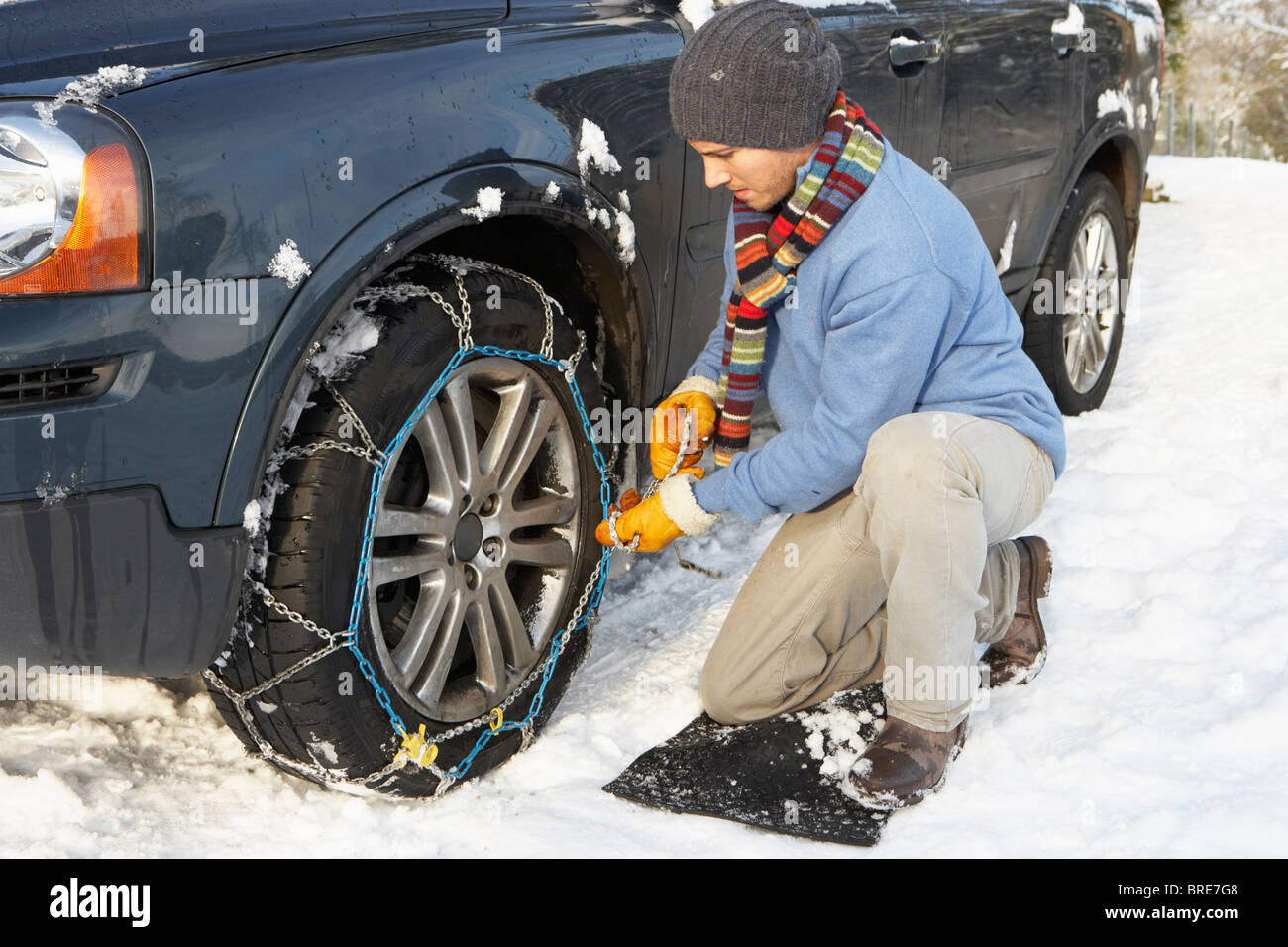 Man Putting Snow Chains Onto Tyre Of Car Stock Photo