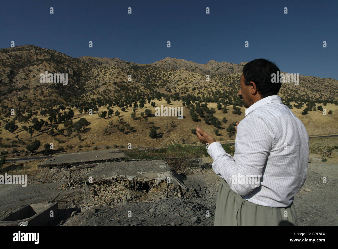 A Kurdish villager praying over a bombarded house which was hit by Iranian artillery targeting Kurdish HPG and  PJAK guerilla fighters in the Qandil Mountains a mountainous area of Iraqi Kurdistan near the Iraq Iran border Stock Photo