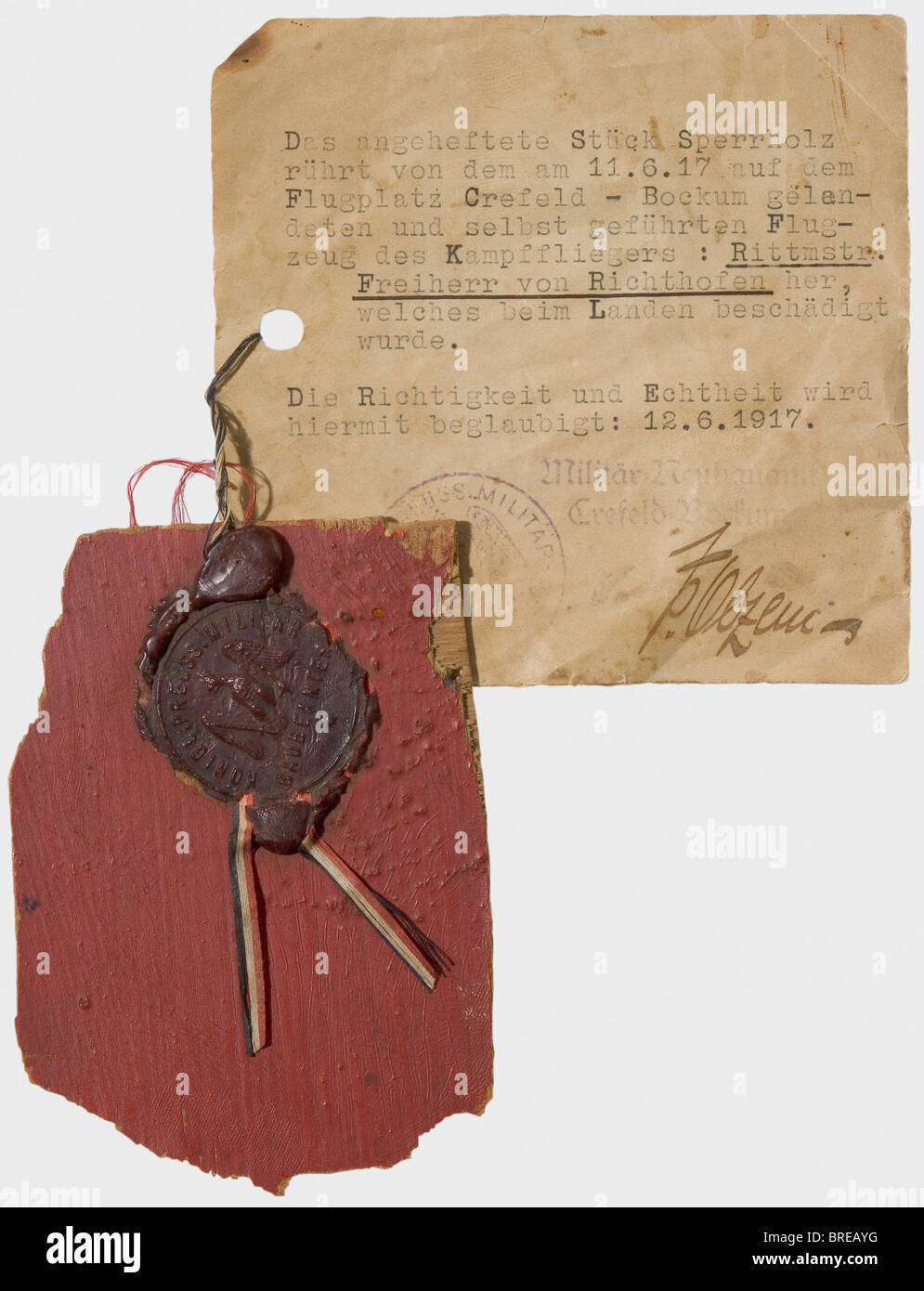 Manfred Freiherr von Richthofen (1892 - 1918), a fragment of the body of an Albatros D V Three-layered plywood, size ca. 72 x 102 mm, painted red on one side, clear coat on the reverse. Attached with sealing wax a typewritten label bearing the inscription (transl.) 'the piece of plywood at hand comes from the aircraft, which landed on 11.6.17 on Crefeld-Bockum airfield. It was flown by combat pilot Cavalry Captain Freiherr von Richthofen and was damaged during the landing manoeuvre. The verification and authenticity is confirmed herewith: 12.6.1917.' With a sta, Stock Photo