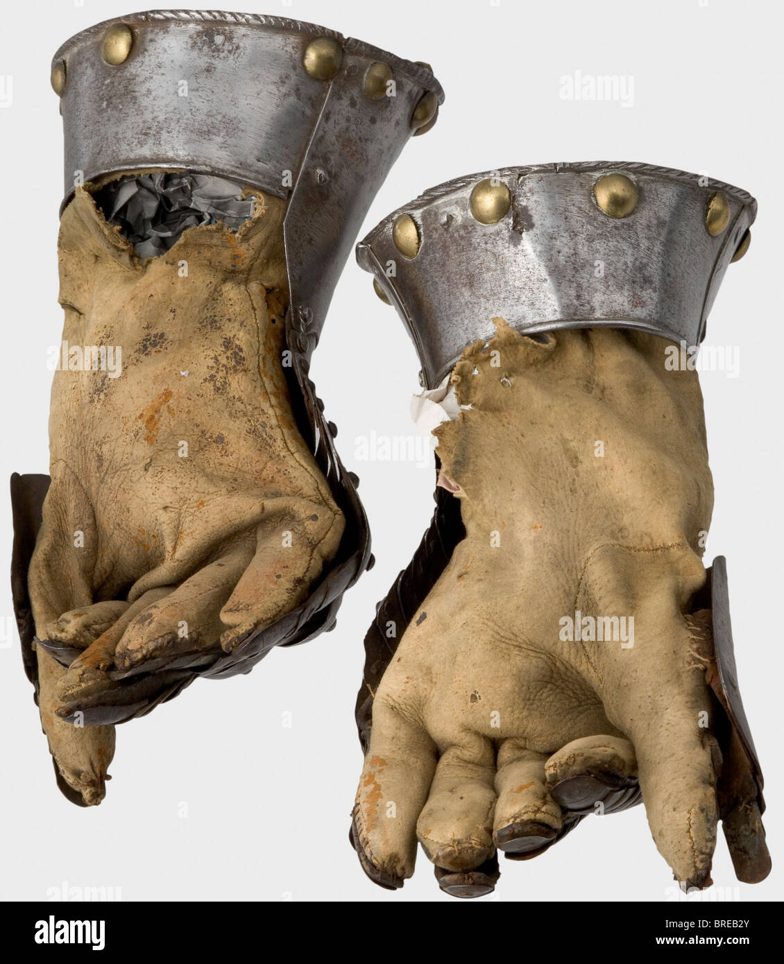 A pair of fingered gauntlets, Germany or Flanders, circa 1600 Metacarpus of six lames. Cambered knuckle-guard with attached articulated overlapping finger plates (one replaced, two missing). Ridged thumb defences with overlapping lames. Ridged pointed cuffs with turned under and roped edges. Large decorative brass rivets along the perimeter (two rivets missing). Sewn-in original lining-gloves of natural coloured, chamois-dressed leather, (marks of age, each damaged at the wrist). Length of each 34 cm. historic, historical,, 17th century, defensive arms, weapons, Stock Photo