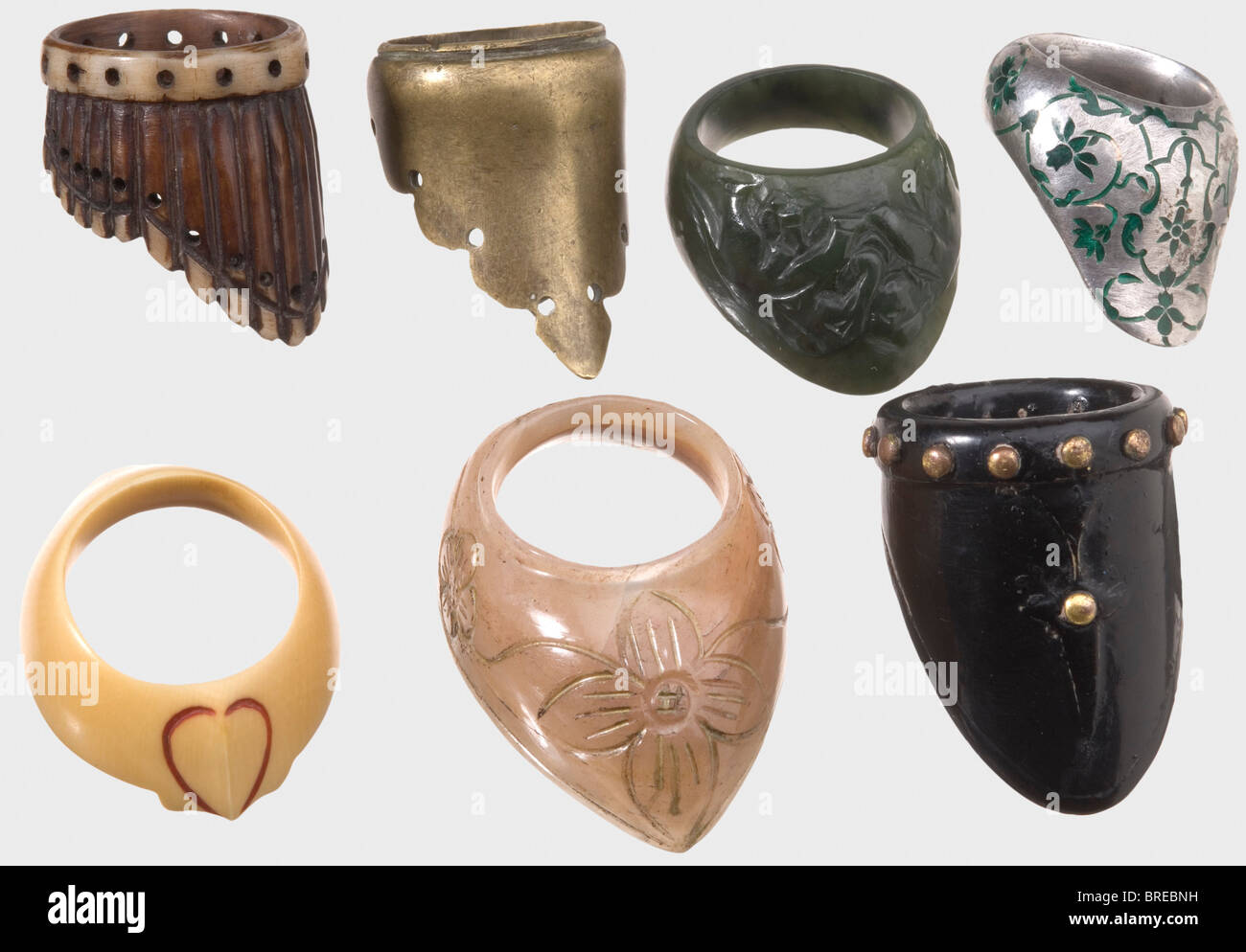 Seven Indian archer's thumb rings, 19th/20th century Different types and materials, made variously of horn, leather, green jade, agate, ivory, brass, and silver with enamelled floral designs. The jade ring is carved with fighting elephants carved, and the leather piece is surrounded with decorative gilt copper rivets. Lengths 40 to 51 mm. historic, historical, 19th century, jewellery, jewelry, noble, precious, object, objects, stills, clipping, clippings, cut out, cut-out, cut-outs, Stock Photo