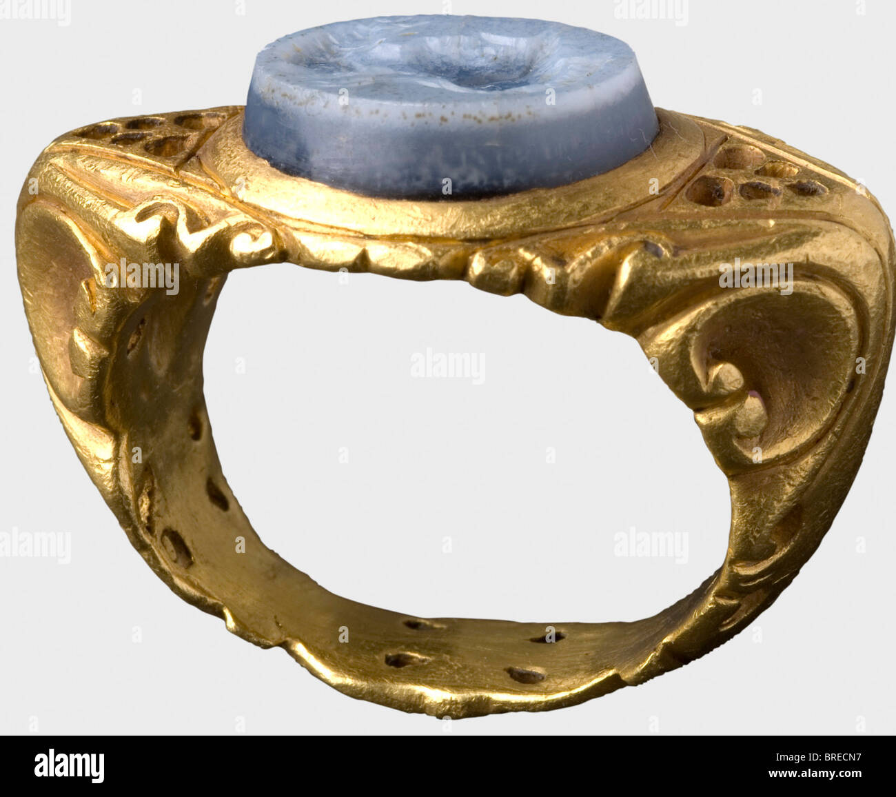 A Roman gold ring with an agate gem, 3rd/4th century A.D. Heavy band with richly engraved openwork decoration. A blue, layered agate set in the top, carved with the head of Minerva. Cleaned excavation discovery. Weight 34 g. historic, historical, ancient world, ancient world, ancient times, object, objects, stills, clipping, cut out, cut-out, cut-outs, jewellery, jewelry, noble, precious, Stock Photo