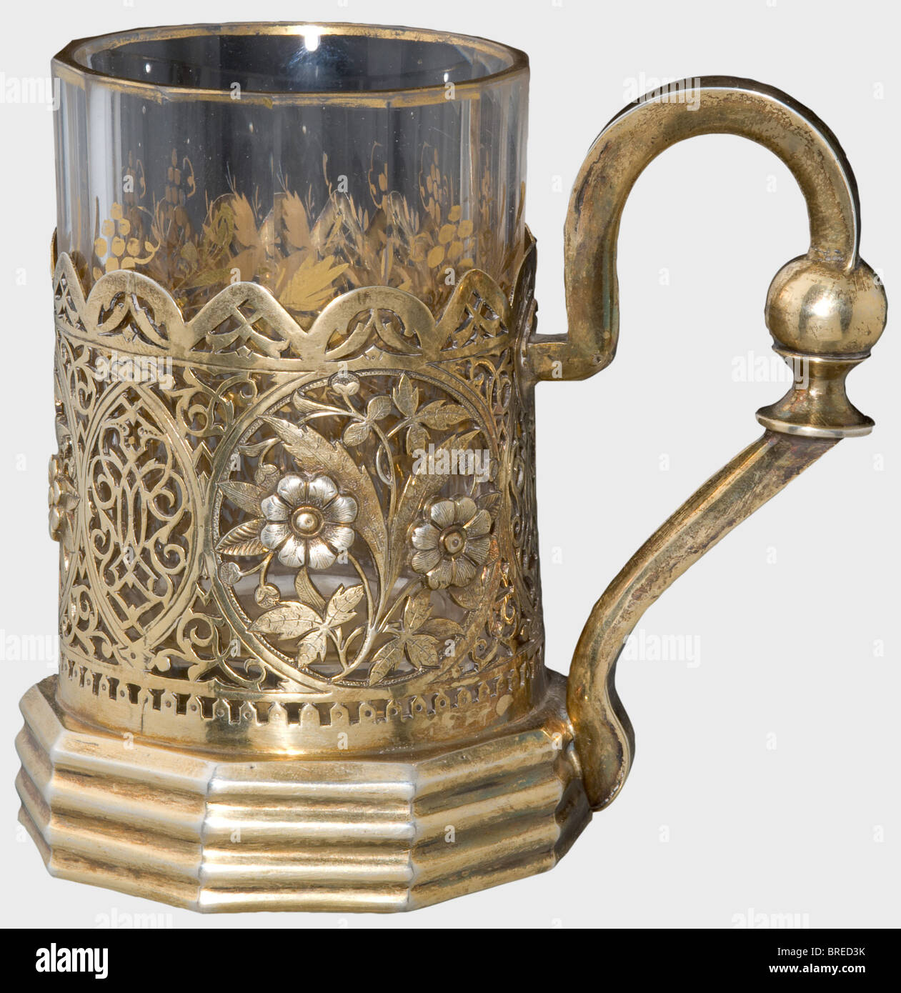 A gilt silver tea glass holder, N. Alexeev, Moscow, 1895 Silver, completely gilt, openwork floral designs. Cyrillic master's mark, 'NA', Moscow hallmark for '84', the Cyrillic inspecting master's mark, 'AS' and the year '1895' are on the bottom. Height 11.4 cm. Weight 192 g. Faceted tea glass with golden floral decoration. Provenance: Grand Duchess Vera Konstantinovna Romanova (1854 - 1912). historic, historical, 1910s, 20th century, 19th century, fine arts, art, art object, art objects, artful, precious, collectible, collector's item, collectibles, collector's, Stock Photo