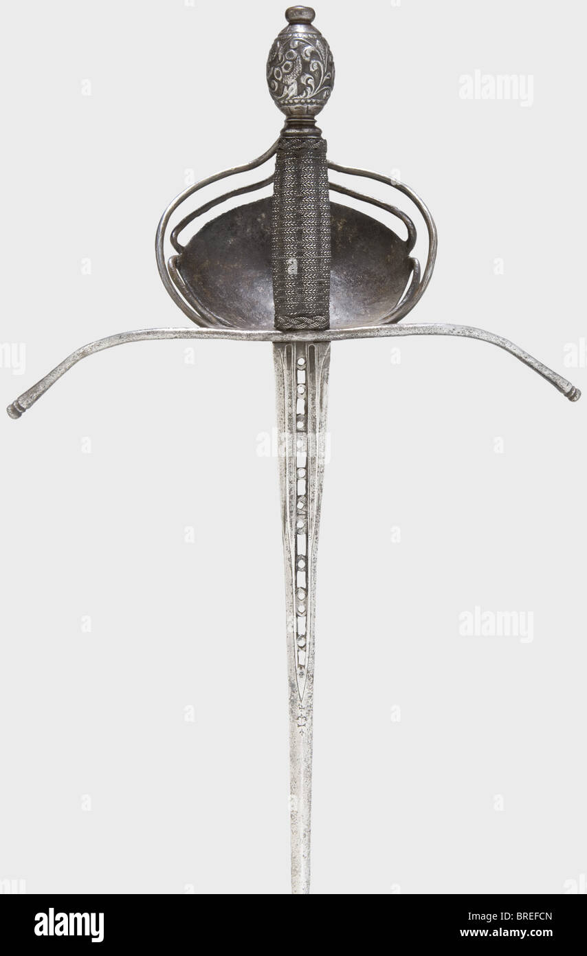 A left-hand dagger, Italy or Spain, circa 1660/70 Slender, ridged thrusting blade, the upper half with a perforated central fuller, the base widened and with triple fullers. The fullers bear stamped crosses and 'AP - ET'. Long, expansive quillons, the shell-like hand-guard with chiselled decoration. Grip with iron wire winding and Turk's heads. Olive-shaped pommel richly cut with tendril decoration. Length 46.5 cm. historic, historical,, 17th century, dagger, daggers, thrusting, thrustings, baton, weapon, arms, weapons, arms, fighting device, object, objects, s, Stock Photo