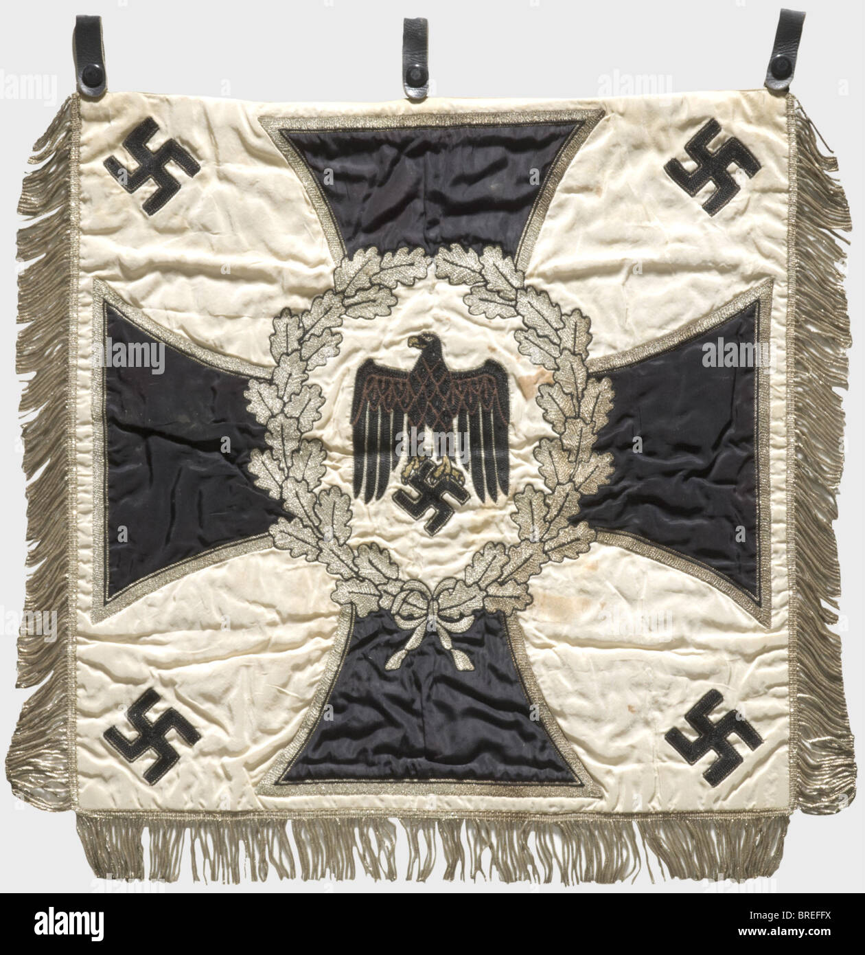 A trumpet banner, of the 1st Battalion/12th Infantry Regiment White silk cloth with an army eagle embroidered in black and brown surrounded by a silver-embroidered oak leaf wreath over an iron cross and four applied swastikas in the corners. Silver fringes on three sides. Three leather loops. On the reverse side the silver-embroidered unit name. Dimensions ca. 53 x 56 cm. Slightly stained, otherwise in very good condition with bright colours. Of great rarity. historic, historical, 1930s, 1930s, 20th century, infantry, military, armed forces, militaria, object, , Stock Photo