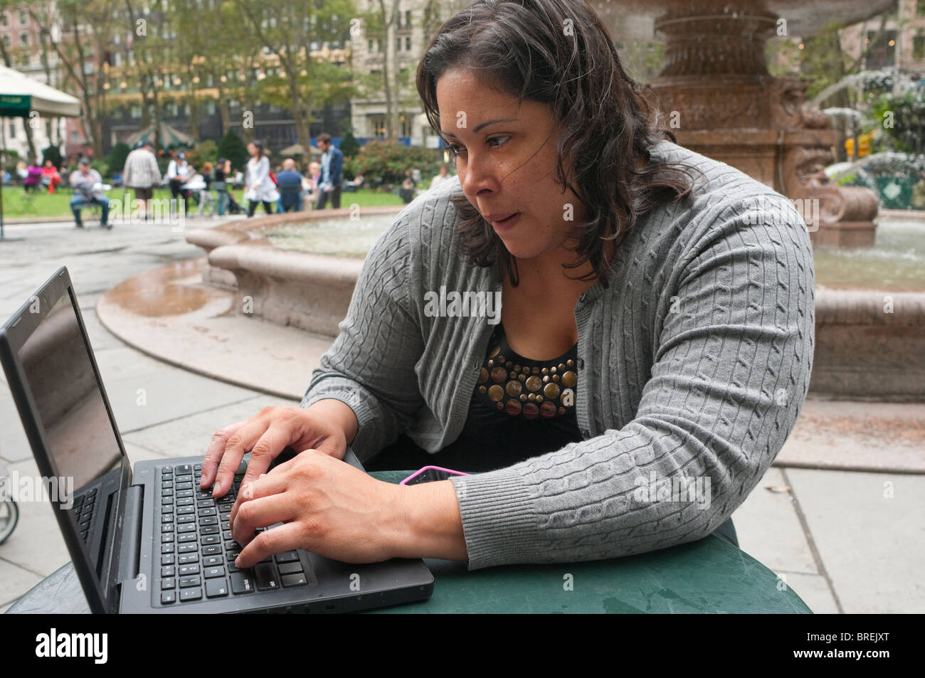 Olga Correa uses a MacBook laptop to access free wireless internet connection in Midtown's Bryant Park Stock Photo