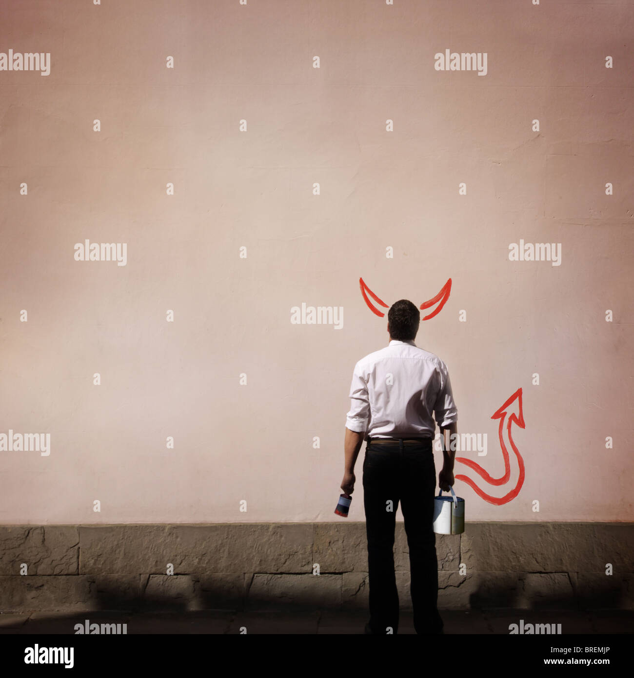 man with devil horns and tail painted on wall Stock Photo