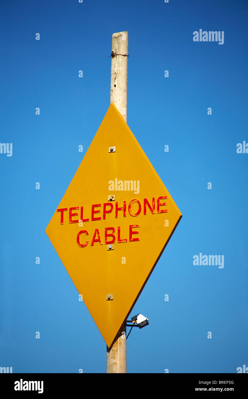 Yellow Telephone Cable sign set against blue sky at UK in August Stock Photo