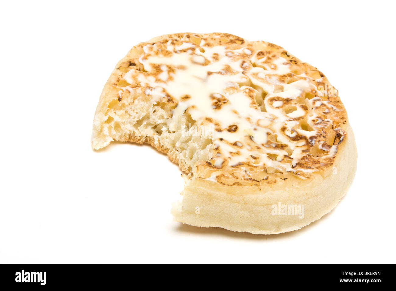 Traditional English Hot Buttered Crumpet with melting butter. Stock Photo