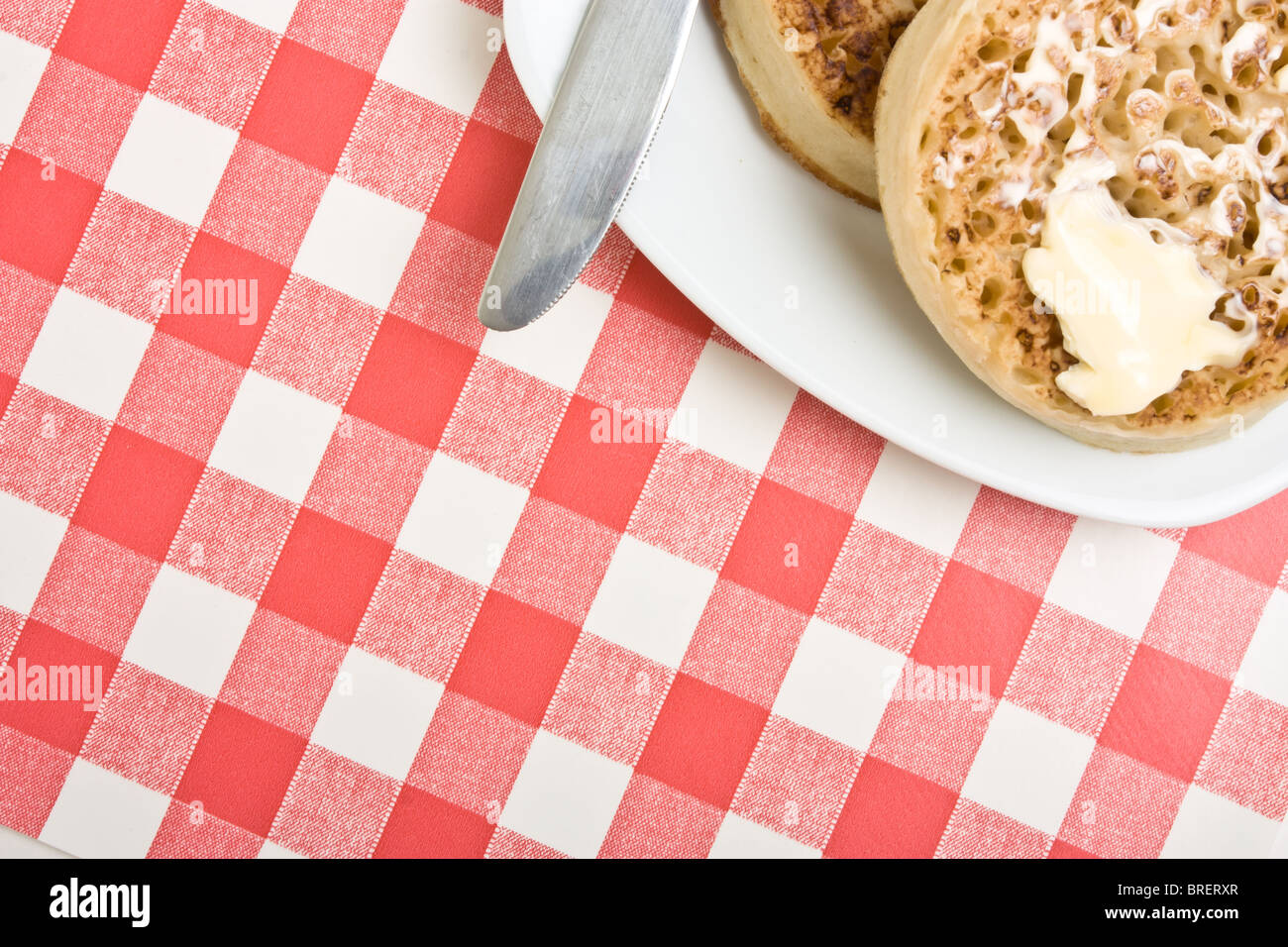 Traditional English Hot Buttered Crumpet with melting butter. Stock Photo