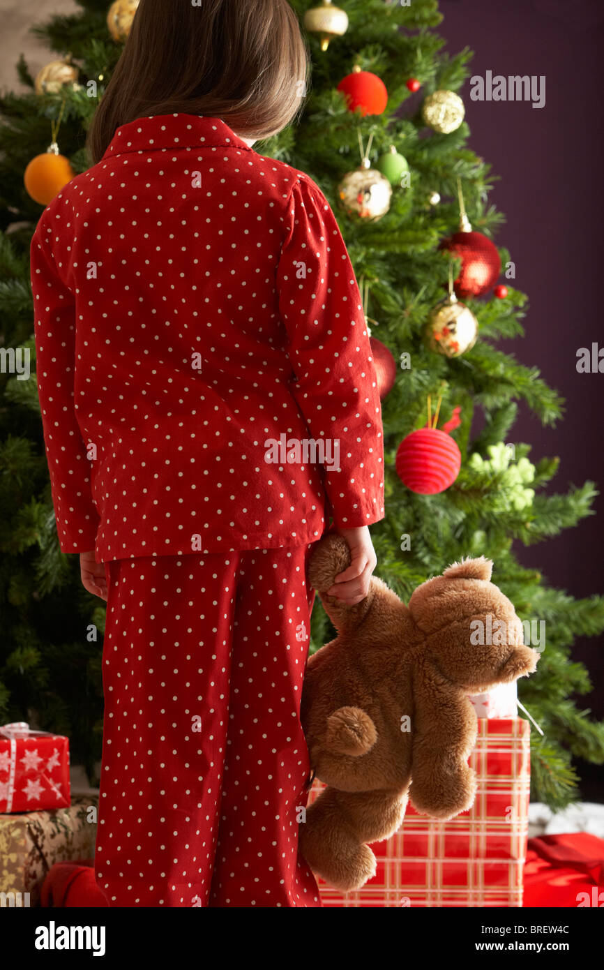 Young Girl Standing With Teddy Bear In Front Of Christmas Tree Stock ...