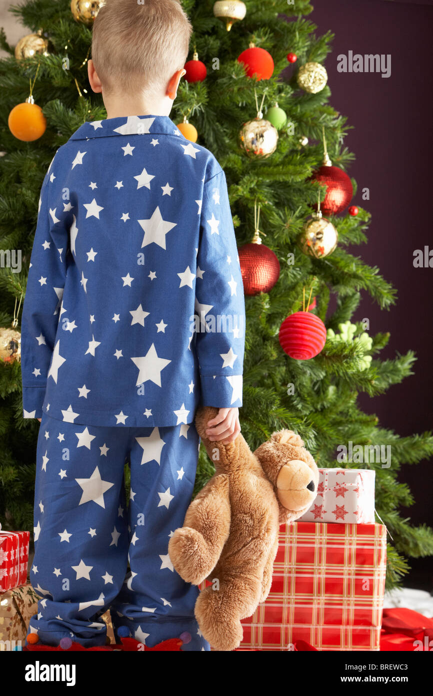 Young Boy Holding Teddy Bear In Front Of Christmas Tree Stock Photo - Alamy