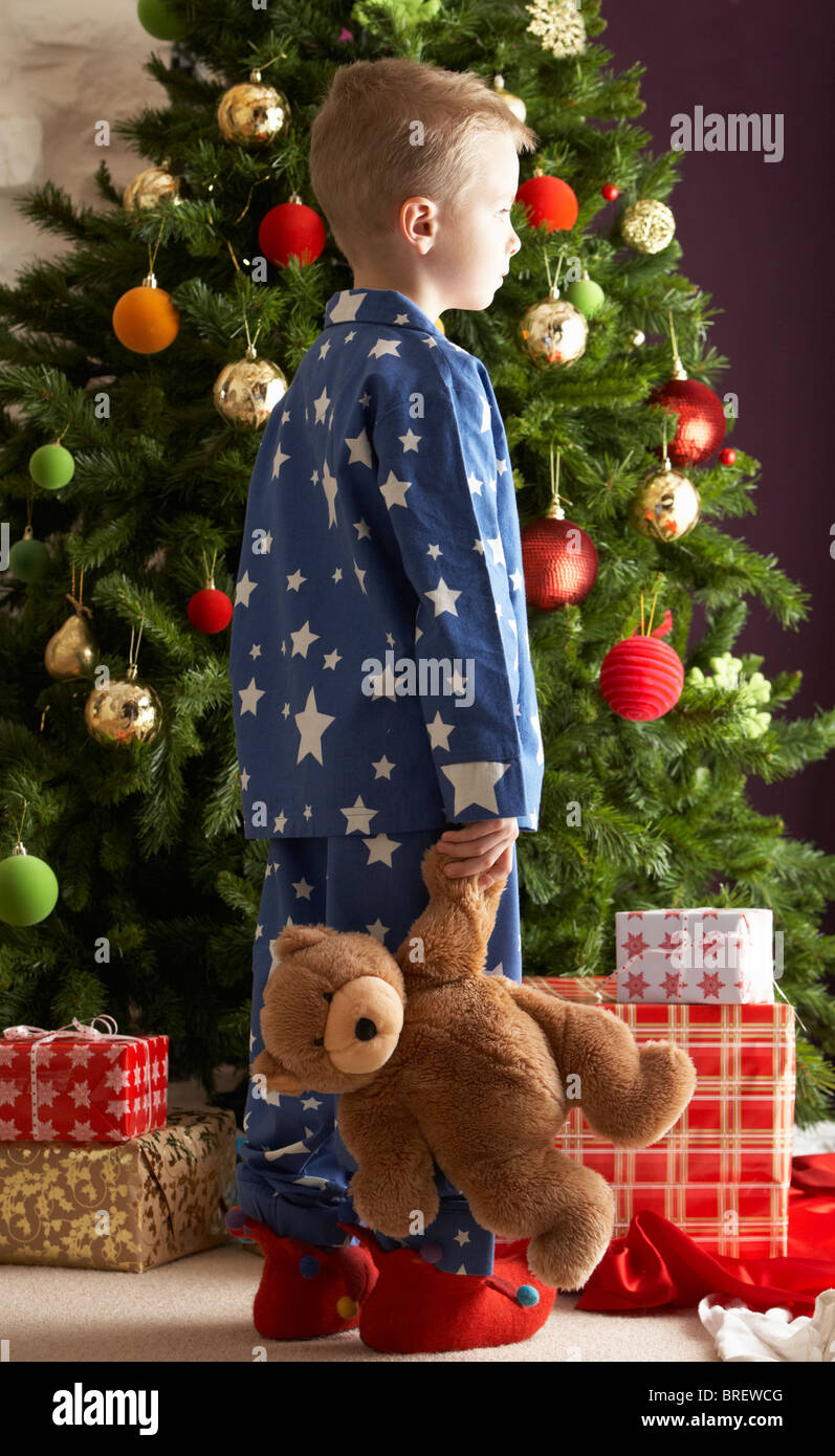 Young Boy Holding Teddy Bear In Front Of Christmas Tree Stock Photo - Alamy